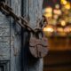 A heavy rusted padlock on a weathered wooden door in a dusty urban setting.Featured Image Description: A cinematic 1:1 macro photograph in conceptual realism. A massive, heavily rusted iron padlock hangs from a thick metal chain on a weathered, gray wooden door. The wood is cracked and peeling, showing years of neglect. In the background, out of focus, the vibrant golden glow of a modern city at night suggests the world moving forward while this door stays shut. The lighting is focused on the texture of the rust and the peeling wood. No people or hands are visible.Featured Image Title: The Cost of Stagnation