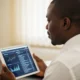 A focused Nigerian official using a tablet to monitor financial data, demonstrating how digital records stop money leakage in government offices.