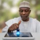 A close-up of a Nigerian citizen using a biometric scanner on a digital tablet for Secure Electronic Voting in Nigeria.