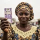 A close-up of a Nigerian market trader holding a 1000 Naira note, representing the Physical Cash King in West African commerce.