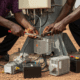 A man in a Nigerian market inspecting a stolen industrial telecommunications battery, representing the impact of Base Transceiver Station Vandalism.