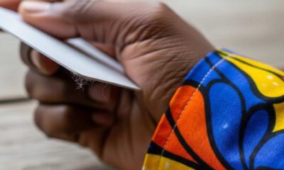 Close-up hand holding a pla against colorful patterned fabric