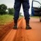 Close-up of a police officer's boots and uniform on a dirt road.
