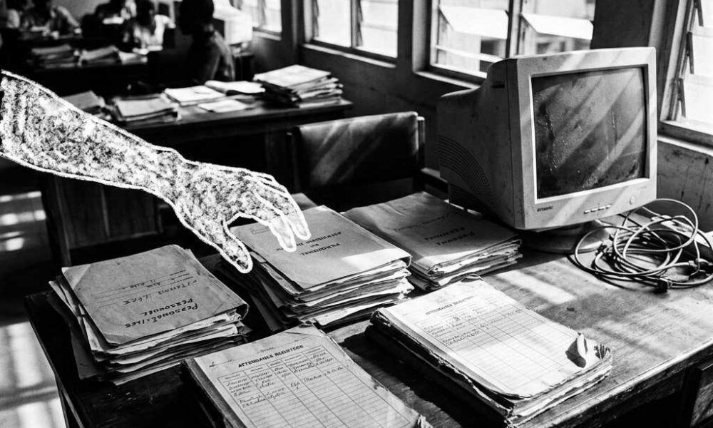 wooden desk stacked with old personnel files and payroll documents