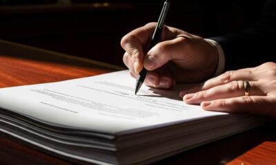 Close-up signing white papers on a dark wooden desk natural light