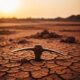 Abandoned mining pickaxe in cracked earth at a Nigerian site at sunset.