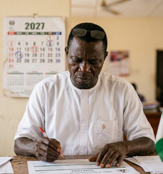 INEC 2027 timetable document on wooden desk with calendar and pen showing election datesFeatured Image Description:
Digital photograph of printed INEC election timetable document spread on a wooden desk surface. A desk calendar open to January 2027 visible beside the document. Red pen resting on paper with certain dates circled. Office background completely blurred. Natural daylight from window. Document shows official INEC header and columns of dates. Photographed from slightly above angle. First quarter 2026.Featured Image Title:
inec-2027-timetable-document-desktop.jpg
