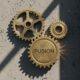 Three interlocking bronze gears symbolizing security agency coordination in Nigeria.