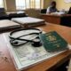 Close-up digital illustration of a dark green passport and a black stethoscope resting on an official tax document.