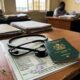 Green Nigerian passport and stethoscope on a tax document