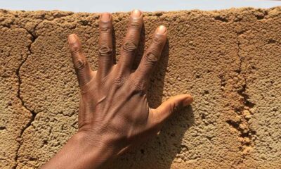 A hand resting on cracked concrete with a frayed electrical cable in the background.