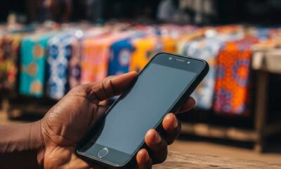 Hand holding smartphone in a sunlit outdoor market