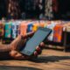 Hand holding smartphone in a sunlit outdoor market