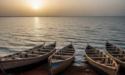 Traditional wooden boats on the shore of Lake Chad at dusk, with the vast lake fading into darkness.