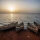 Traditional wooden boats on the shore of Lake Chad at dusk, with the vast lake fading into darkness.