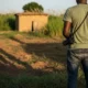 Man on land with shack. Ogun State.