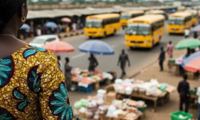 Person watches yellow buses near market stalls.