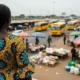 Person watches yellow buses near market stalls.