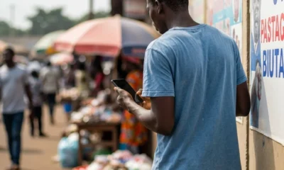 Man with phone faces wall in Lagos market.