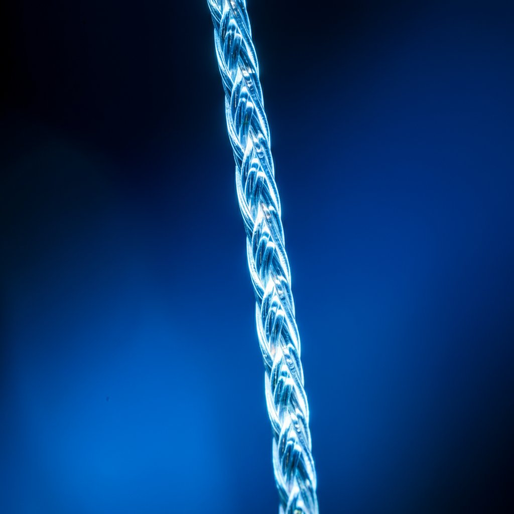 A thick braided cord glows with an internal blue light, snaking across a dark surface. The light pulses gently, like a heartbeat. The cord is not just a connection. It is a conduit for something alive.