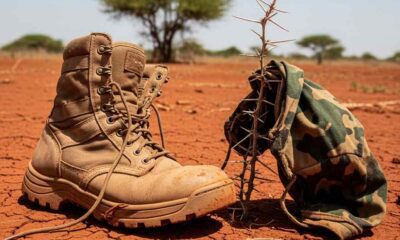 A weathered tactical boot and a scrap fabric lie soil