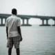 Person looks at Lagos Lagoon; Third Mainland Bridge in soft focus.