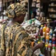 Woman views herbal drinks at Nigeria market.