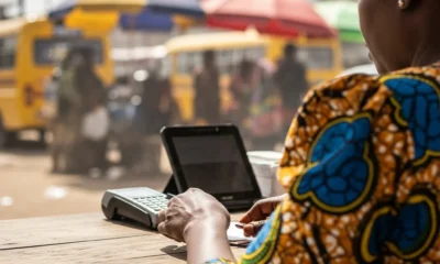 Woman counts naira near POS terminal in Lagos.