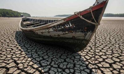 A wooden bo on a cracked, dry riverbed under a bright sun