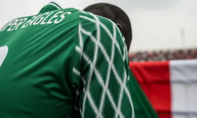 Super Eagles jersey, head bowed.