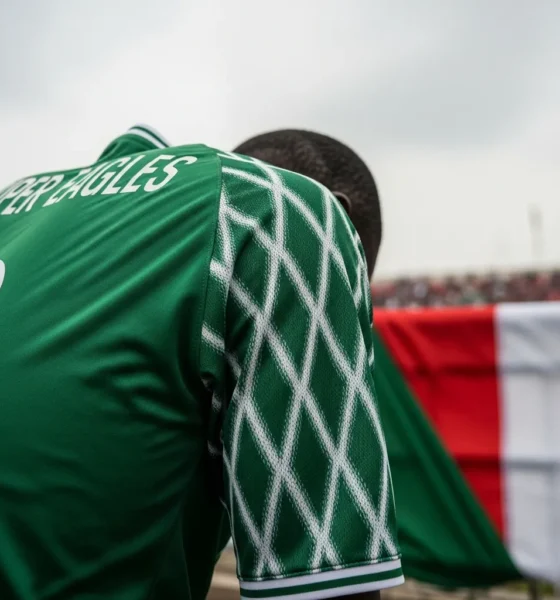 Super Eagles jersey, head bowed.