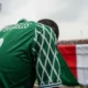Super Eagles jersey, head bowed.