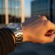 Silver wristwatch on wrist with building background