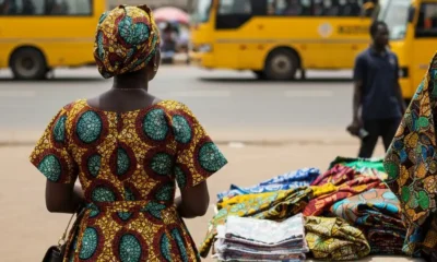 Woman at market in Nigeria looks at fabrics.