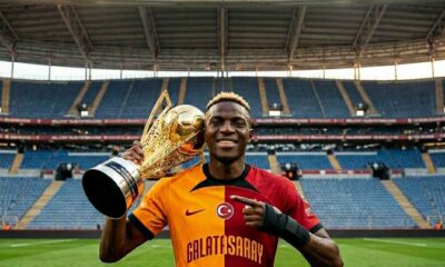 Victor Osimhen in a Galatasaray jersey (yellow and red halves) standing triumphantly on the pitch at RAMS Park in Istanbul. He is raising a large golden football trophy to the crowd. A medical brace is visible on his right forearm. In the background, thousands of blurred fans hold yellow and red flares and "ultrAslan" flags.